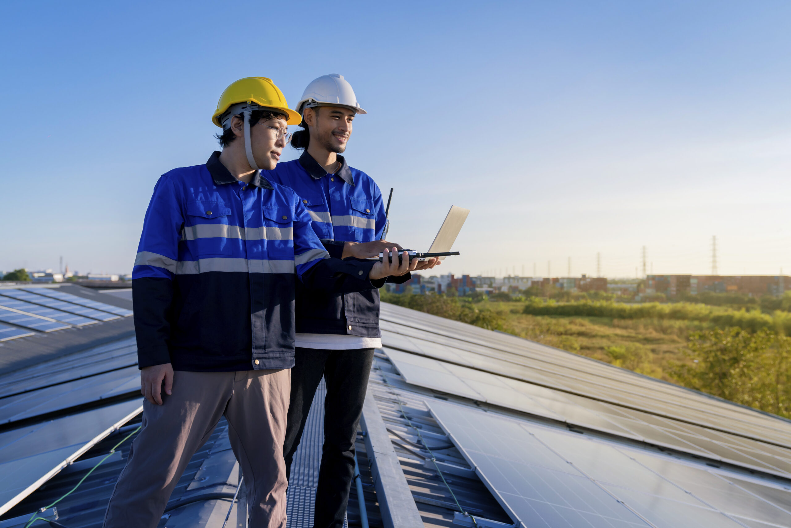 Specialist technician professional engineer with laptop and tablet maintenance checking installing solar roof panel on the factory rooftop under sunlight. Engineers team survey check solar panel roof.